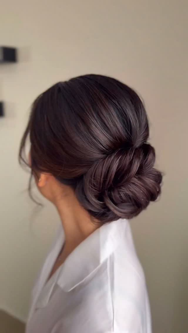 Dark brown hair styled in a low, elegant chignon bun from behind.