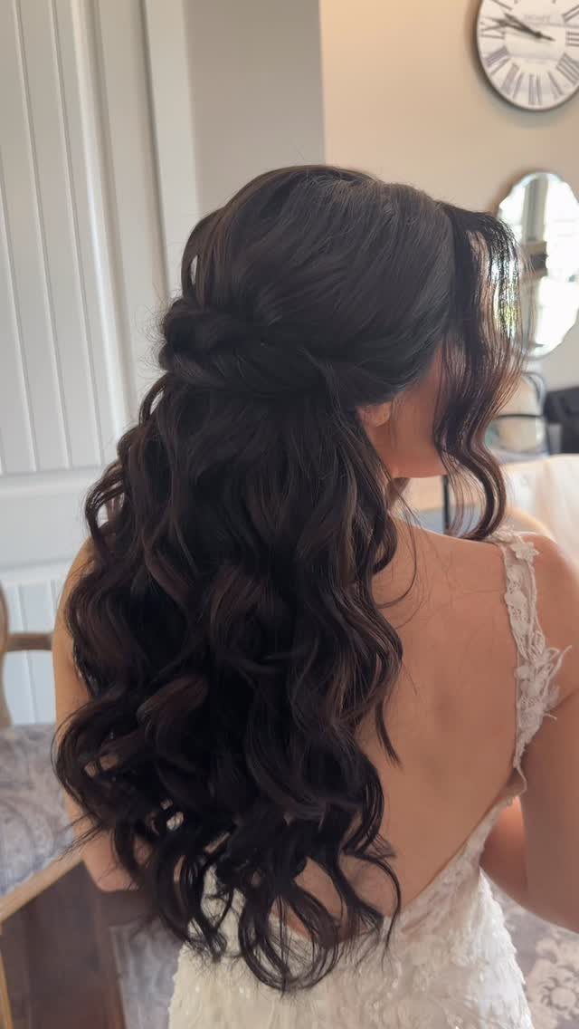 Woman with dark curly hair in a half-up half-down style wearing white lace.