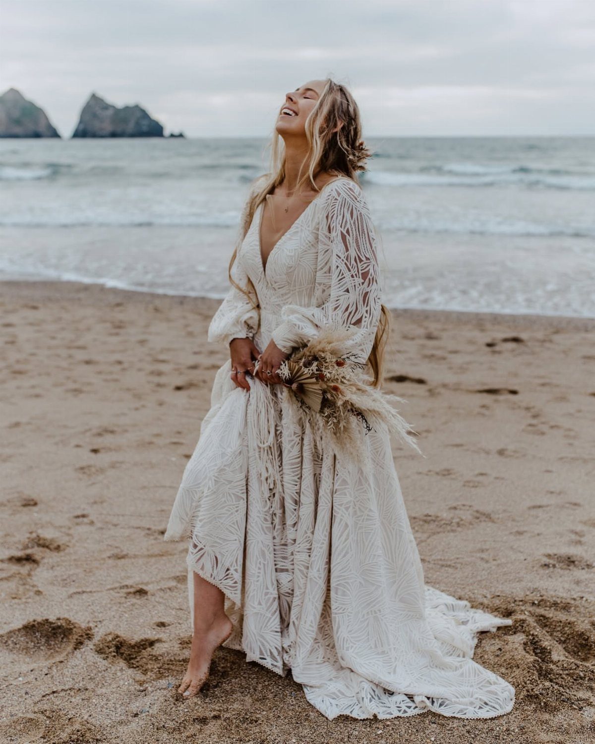 Woman in lace wedding dress with loose blonde waves on a sandy beach