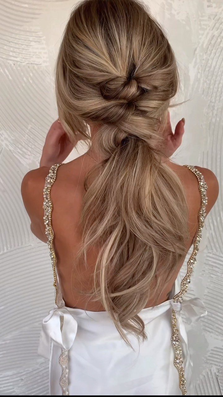 Blonde hair styled in a loose low ponytail with a twisted detail
