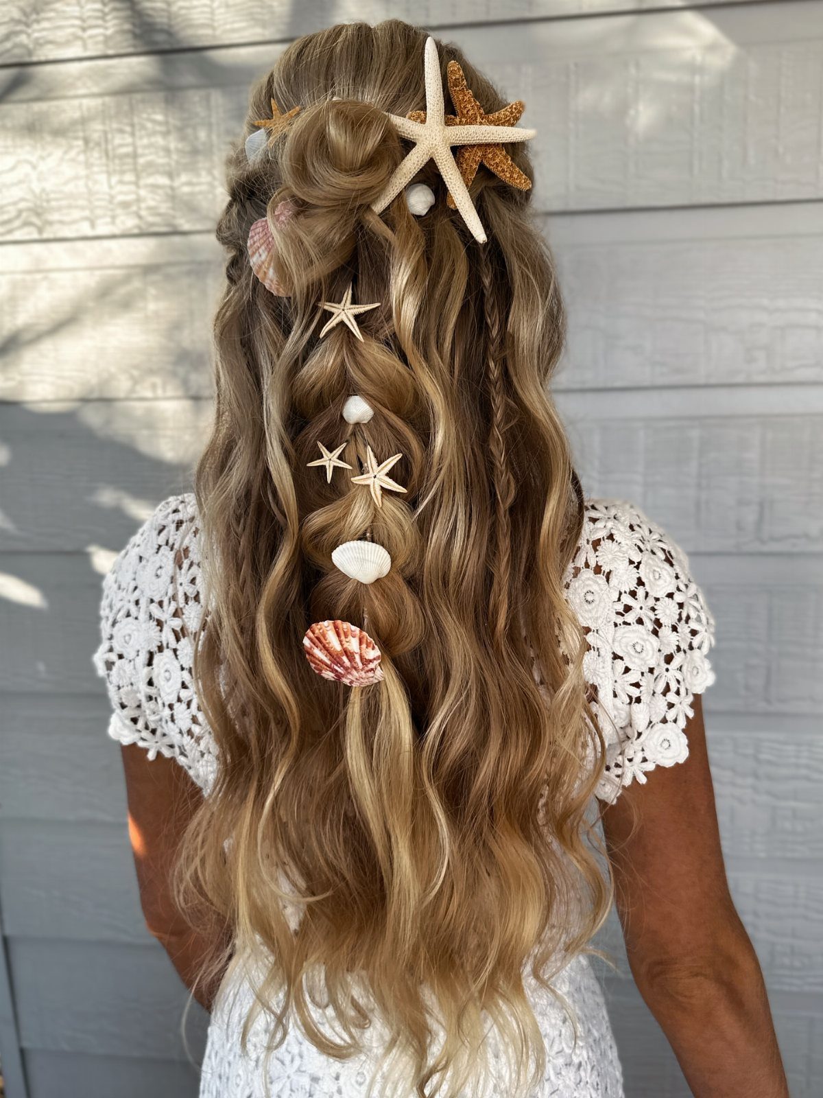 Long blonde wavy hair decorated with starfish and seashells for a mermaid look