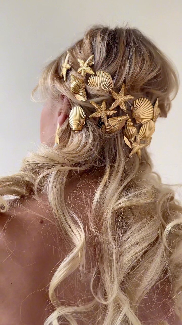 Blonde wavy hair styled with gold metallic seashells and starfish hair accessories.
