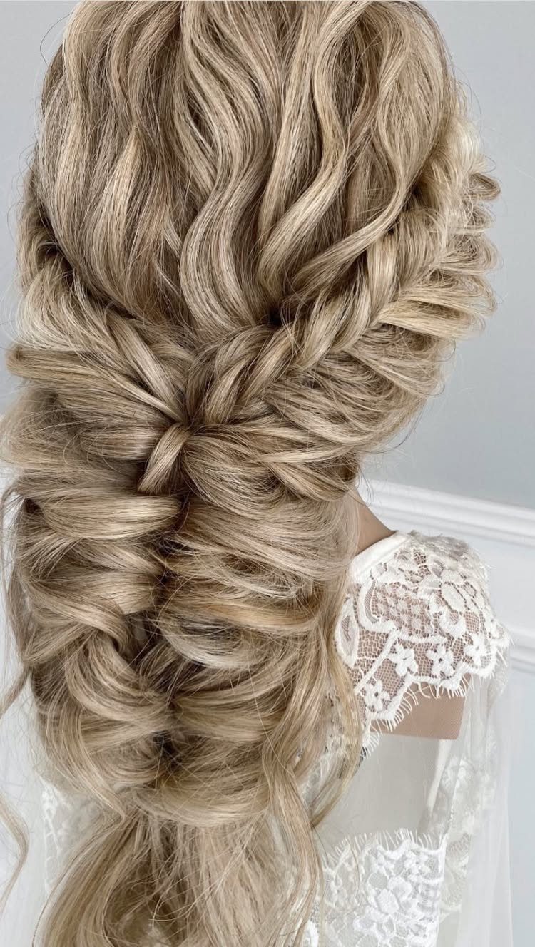 Voluminous blonde braided hairstyle with loose waves and white lace bridal dress