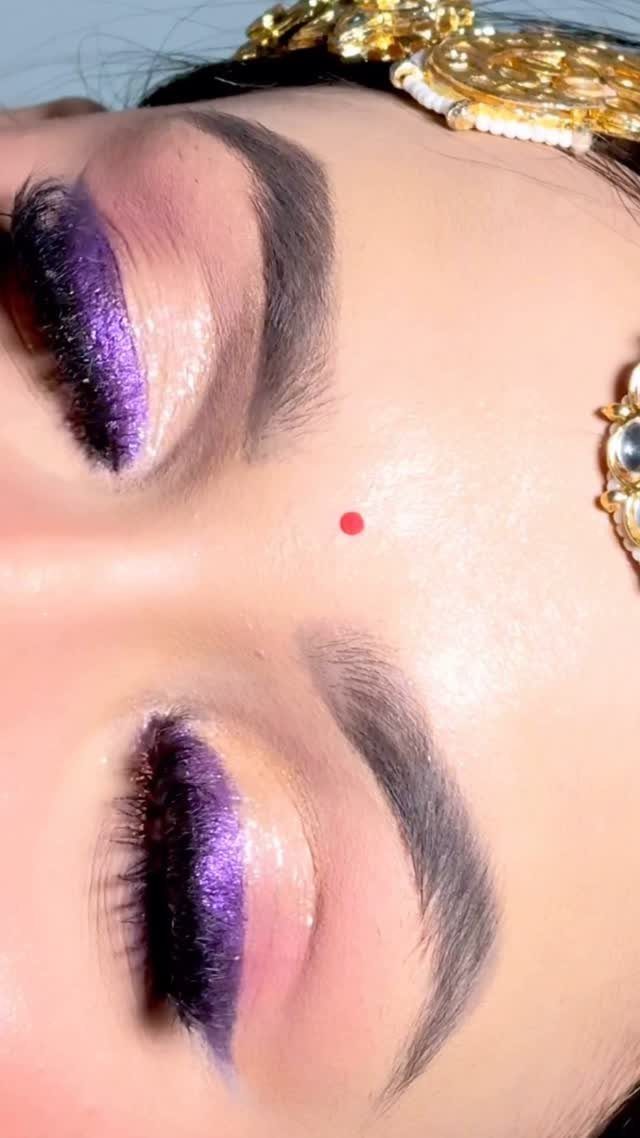 Eyes with shimmering purple eyeshadow, dark liner, and a gold bridal headpiece.