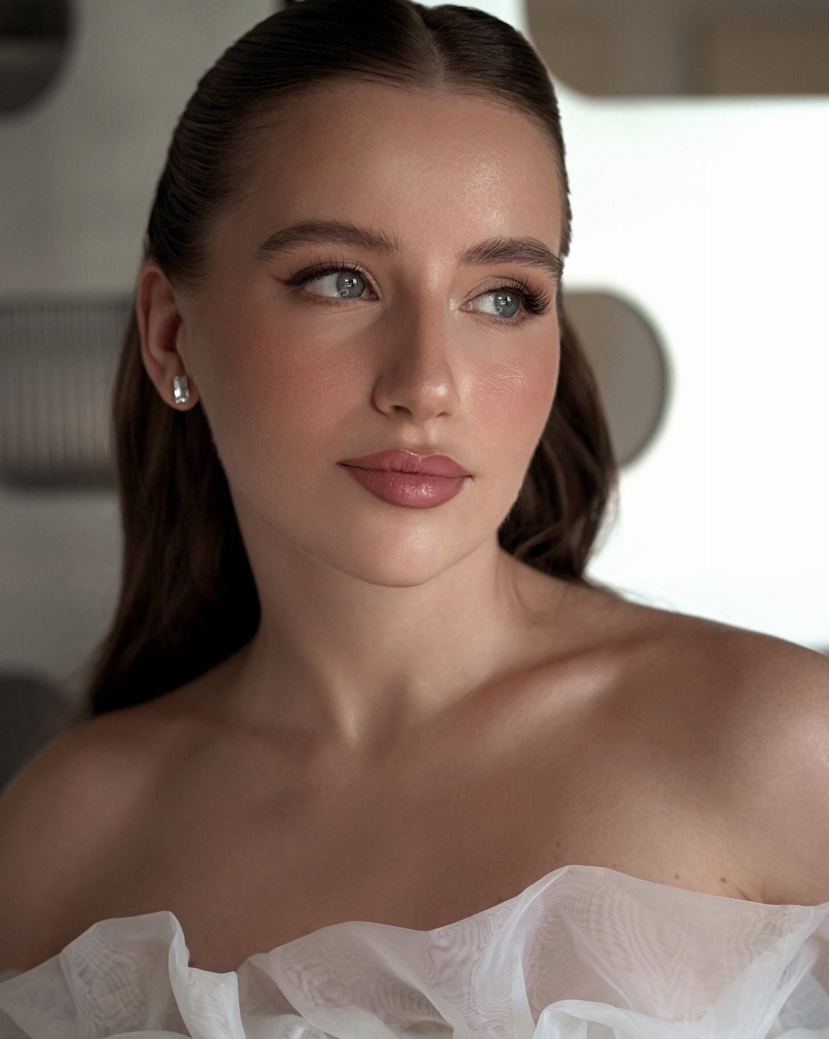 Woman with soft romantic bridal eye makeup and pink lips wearing white ruffles.