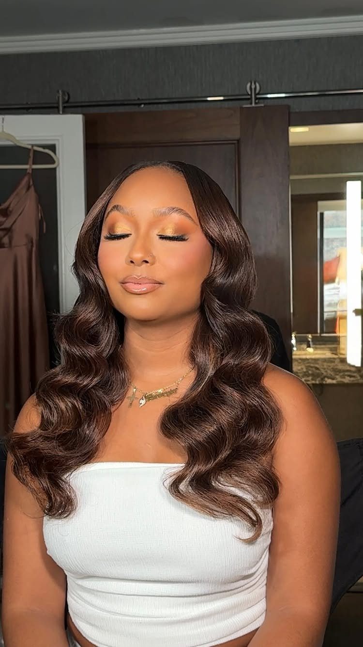 Woman with long brown wavy hair styled in a blowout with middle part