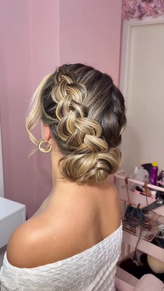 Woman with blonde and brown hair in an intricate braided low bun updo.