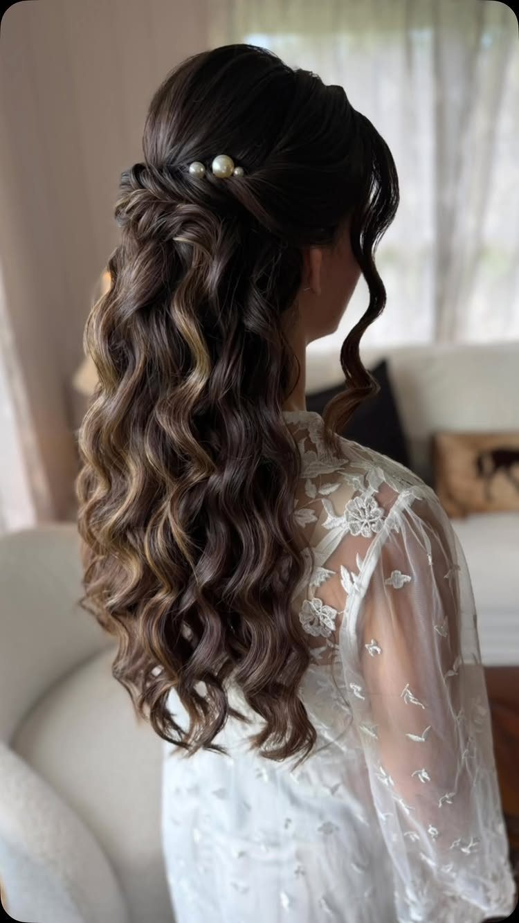 Woman with long brown curly hair in a half-up half-down bridal style with pearls