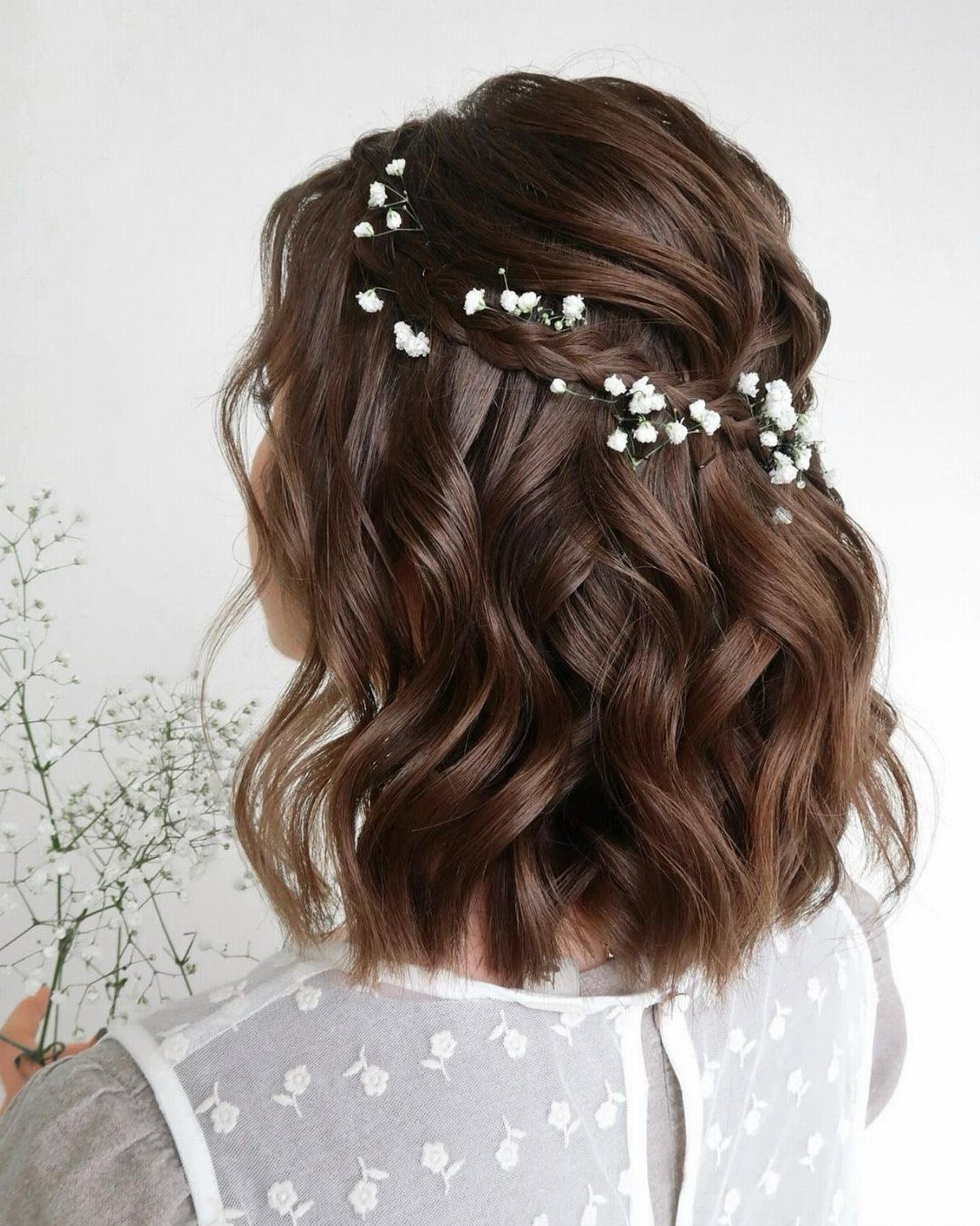 Shoulder-length brown wavy hair with a small braid and white baby's breath flowers.