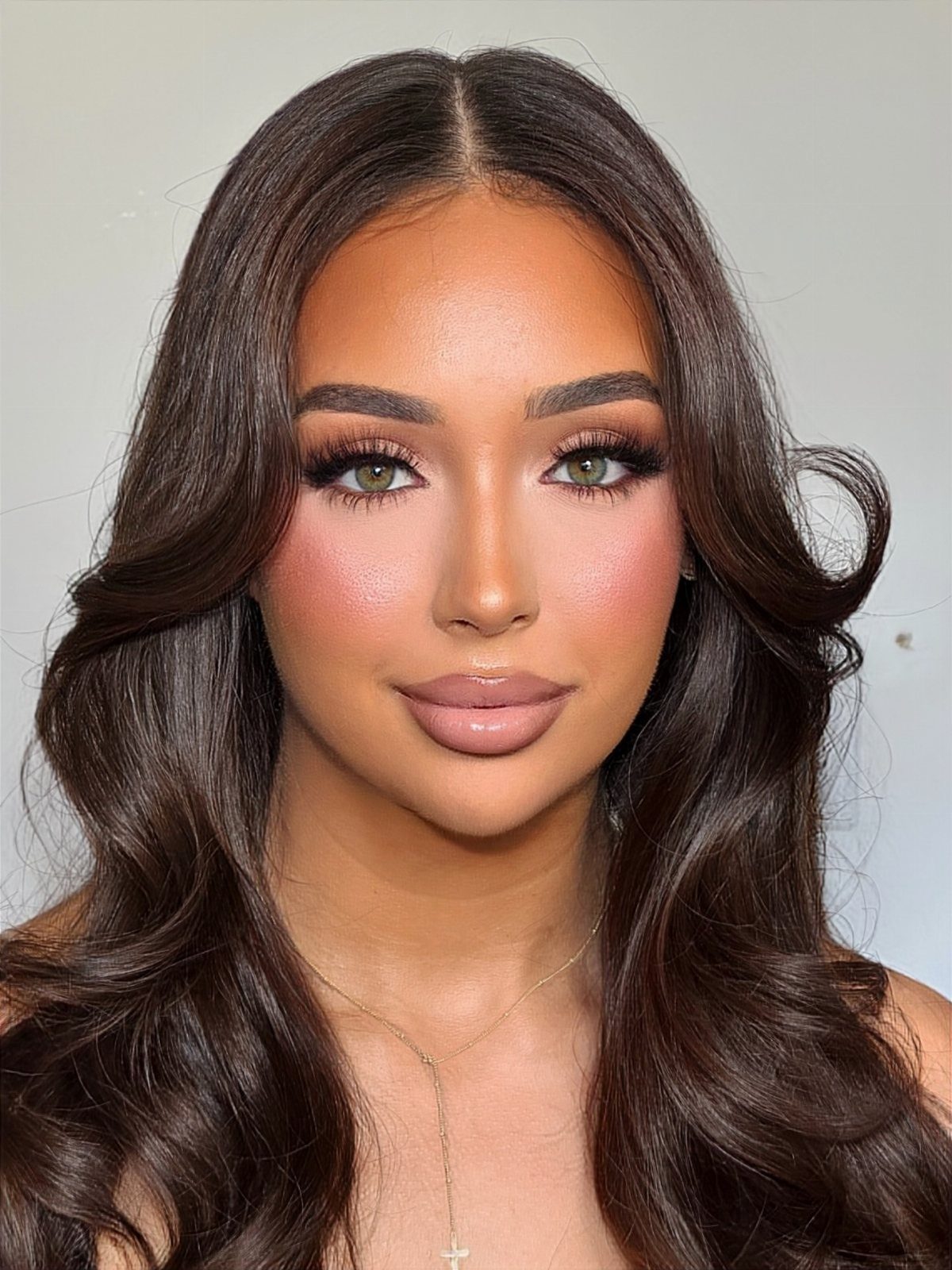 Woman with glamorous wedding makeup, bold eyeshadow, and long wavy brown hair.