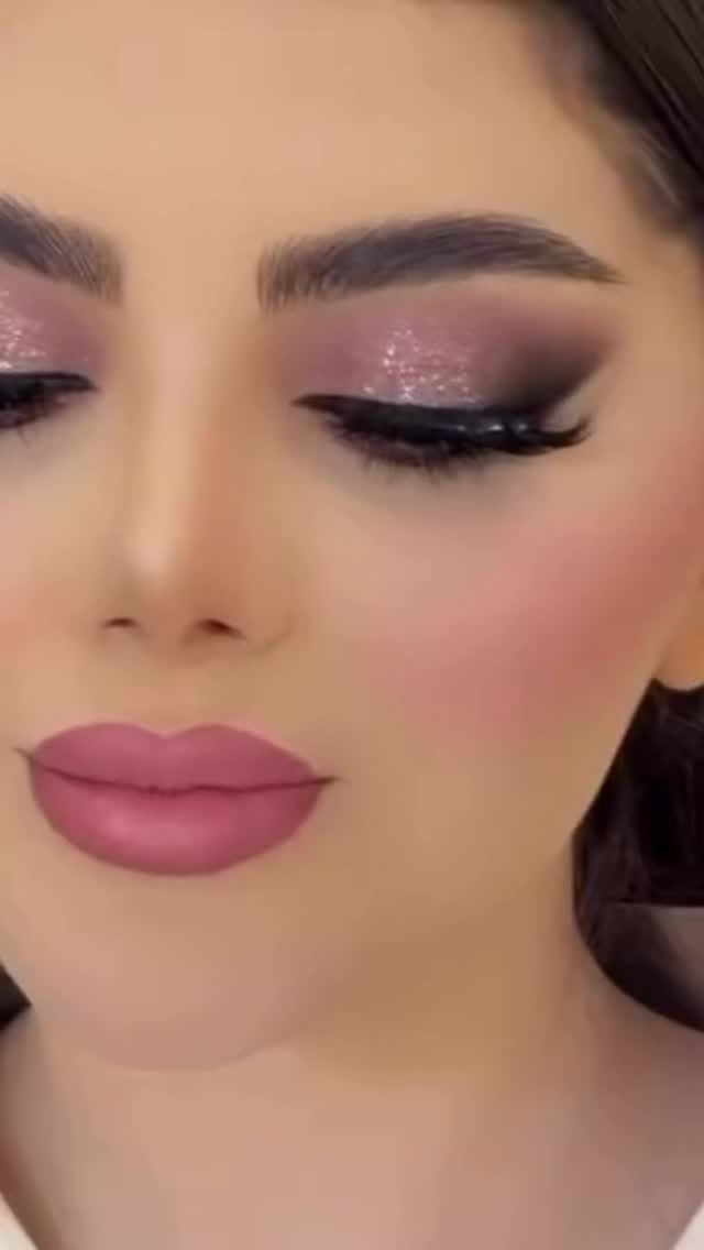 Woman with shimmering pink eyeshadow, winged eyeliner, and matte mauve lipstick.