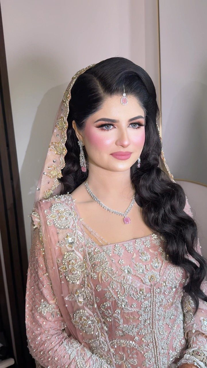Woman in pink bridal attire with pink eyeshadow, pink lips, and silver jewelry.
