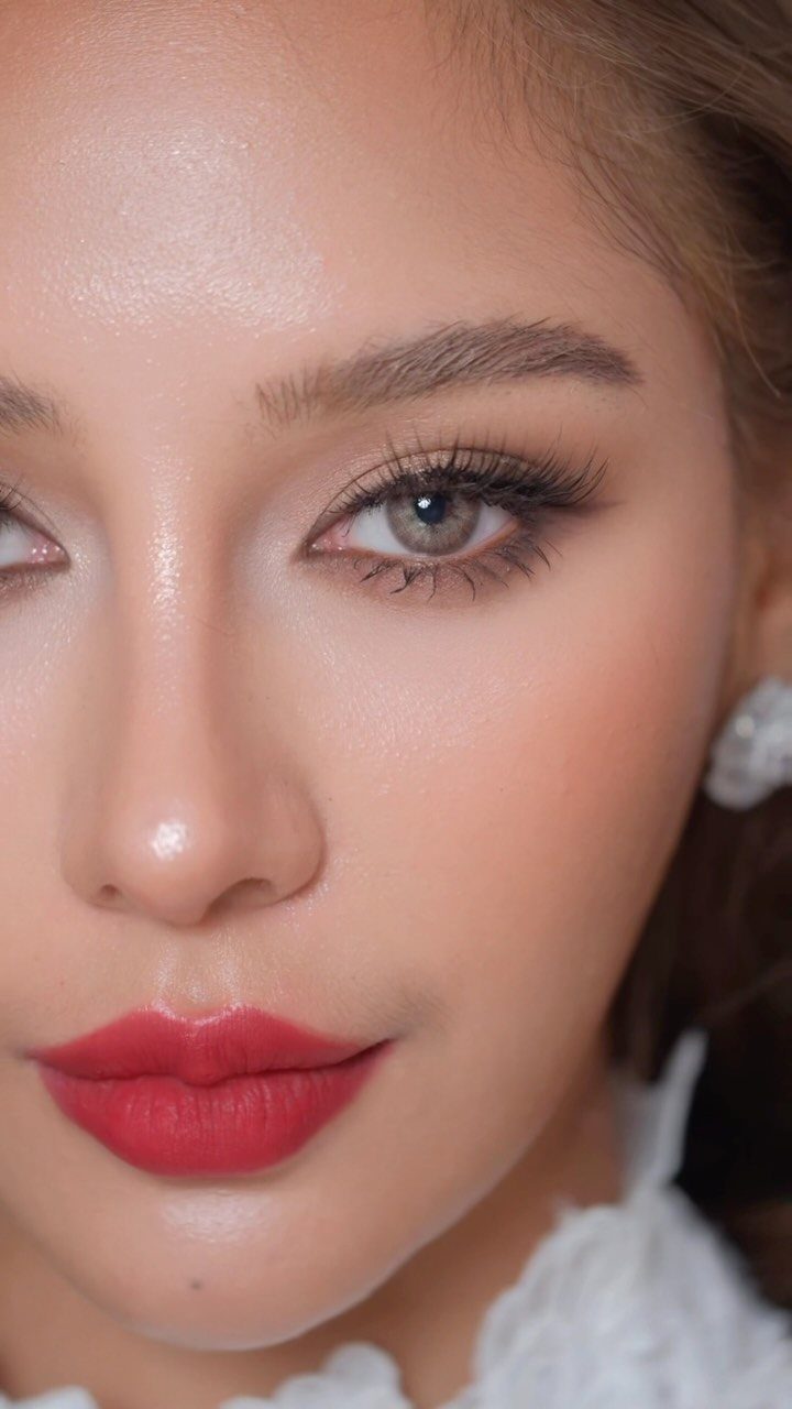 Woman with bold red lips and defined eyelashes wearing white bridal lace.