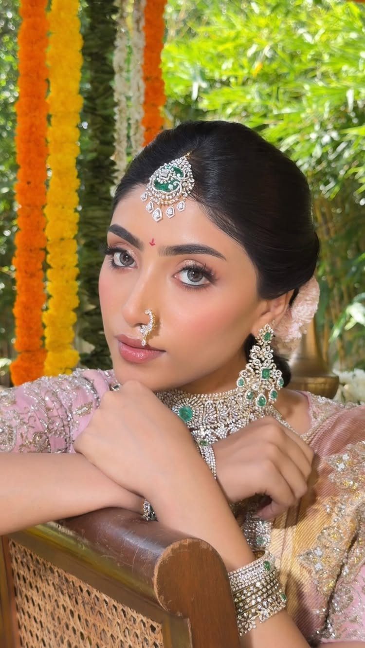 Bride with earthy tone makeup wearing traditional silver and emerald Indian jewelry