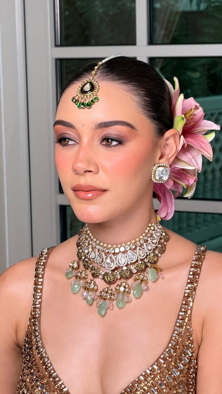 Woman in Indian bridal attire with natural makeup and ornate gold jewelry