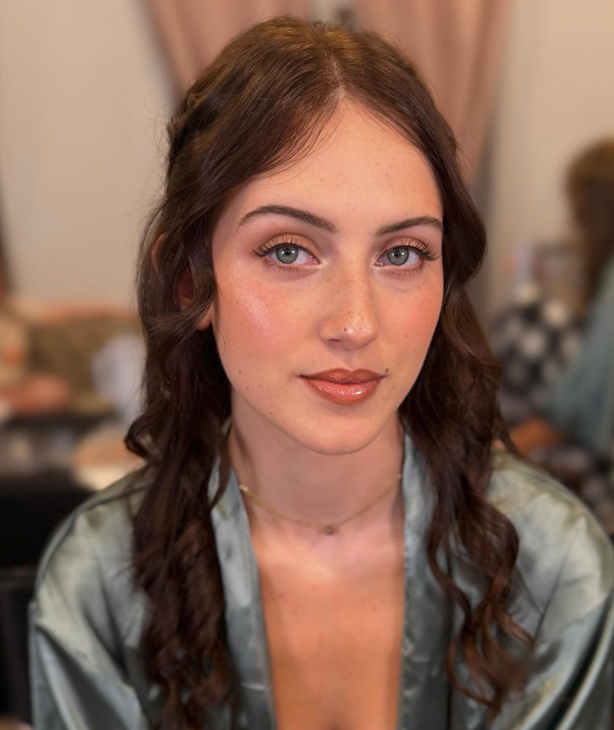 Woman with natural makeup and visible freckles wearing a silver satin robe.