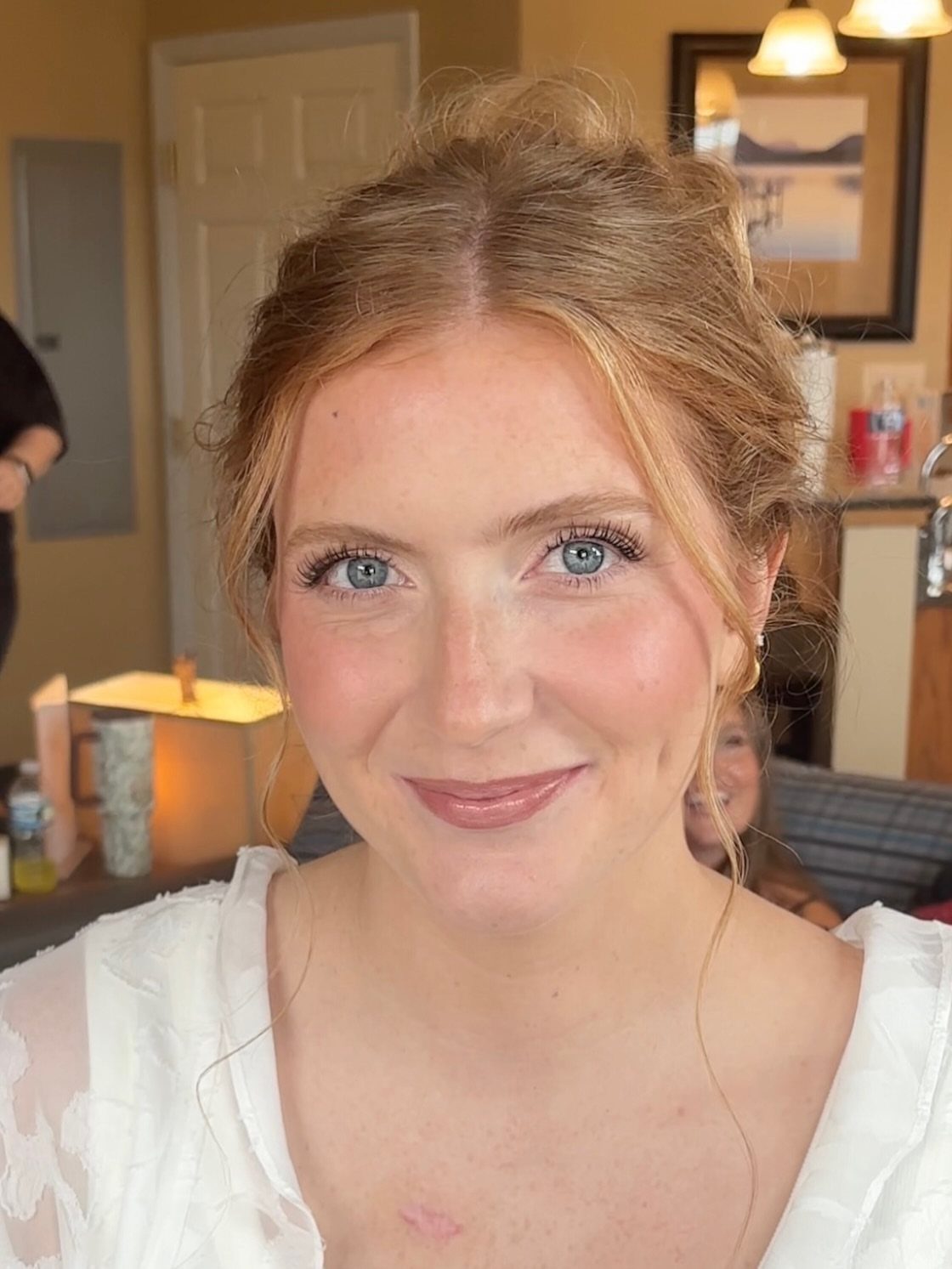 Woman with natural bridal makeup, soft pink lips, and light brown hair updo.