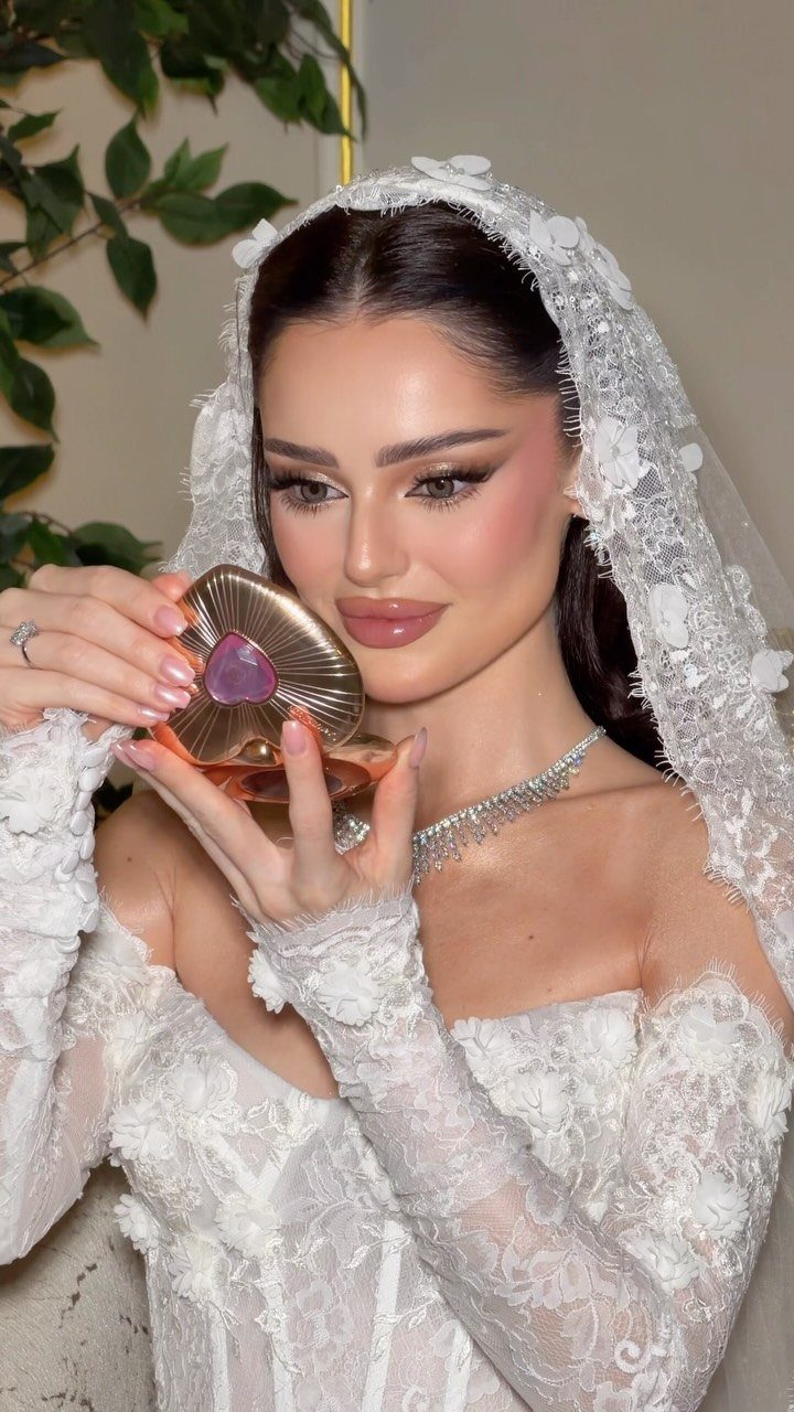 Bride in lace gown and veil showing off long fluttery eyelashes and glam makeup