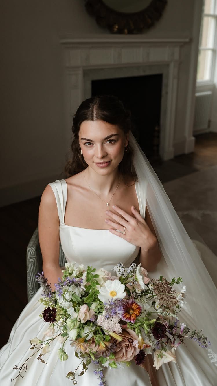 Bride with matte cloud skin makeup holding a colorful wildflower bouquet