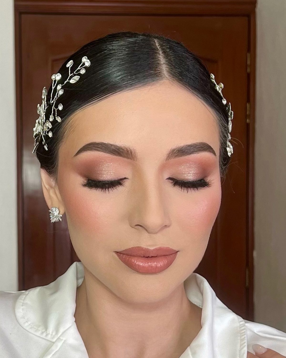 Woman with soft pink and champagne bridal makeup and silver floral hair accessory.