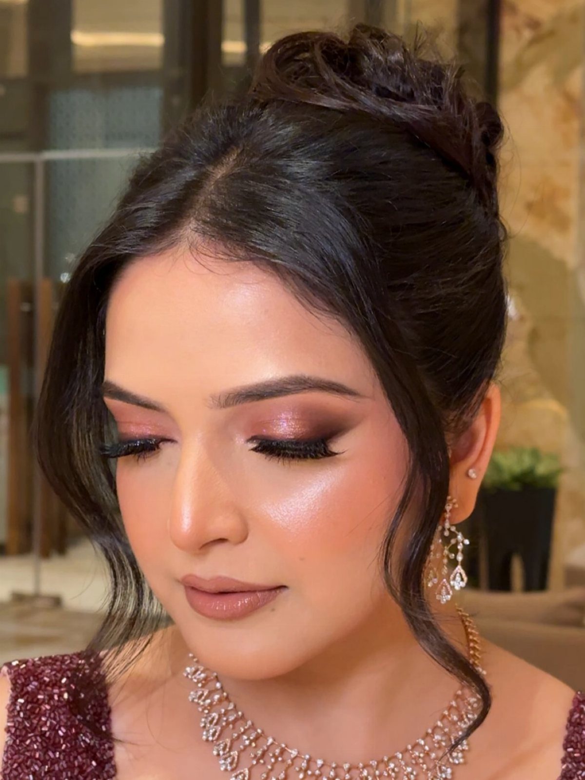 Woman with soft smoky eye makeup, nude lips, and elegant bridal jewelry.