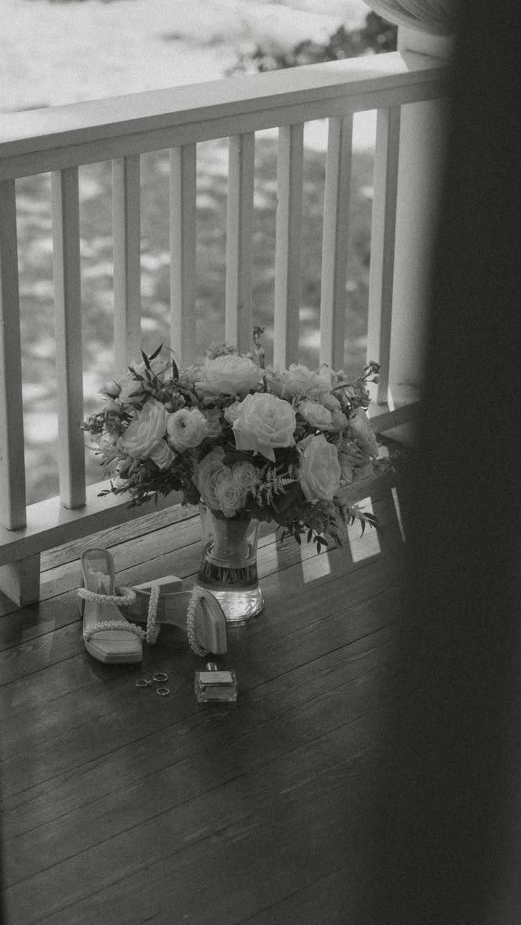 Bridal bouquet in a vase with high heels and rings on a porch.