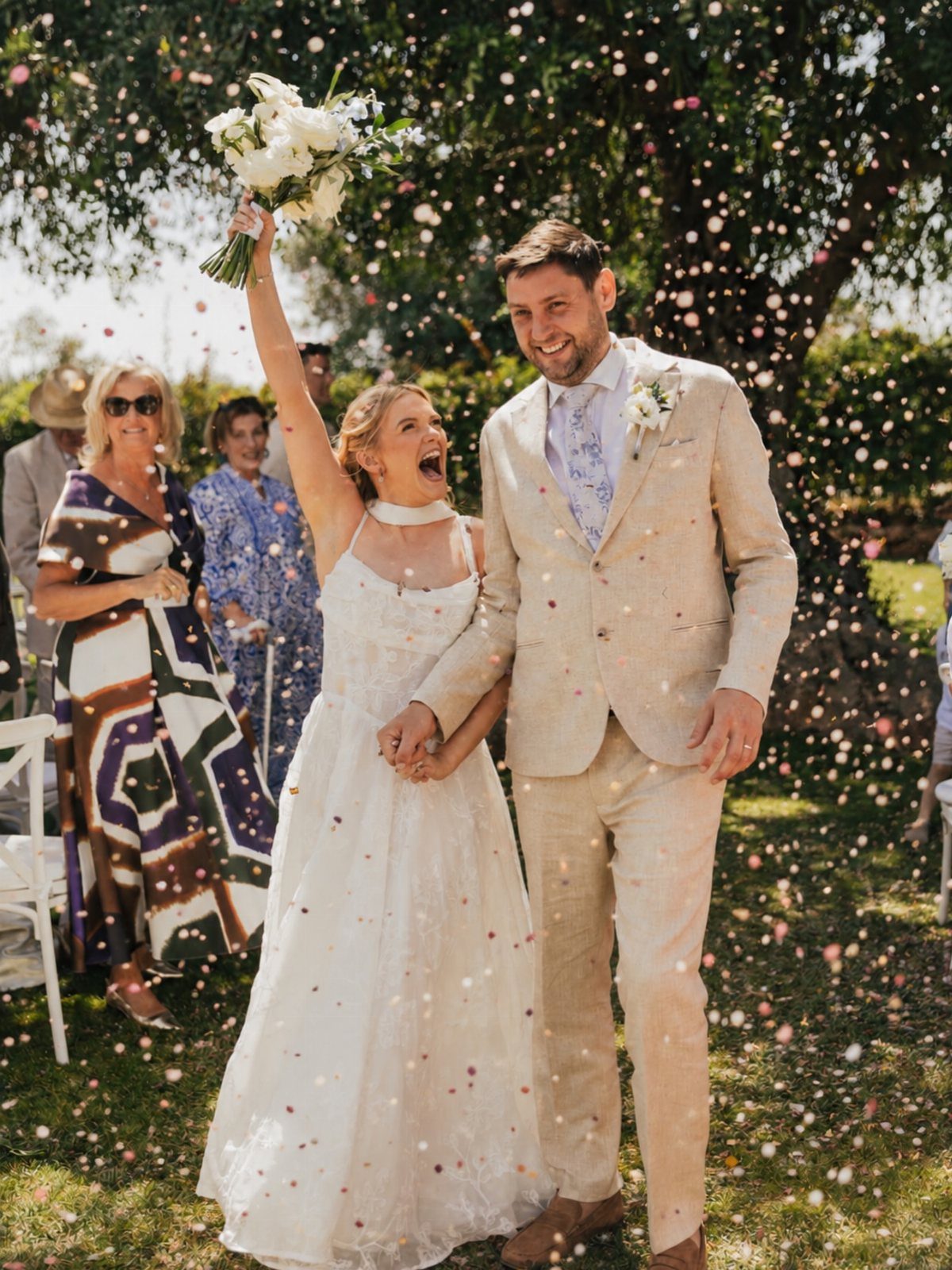 Bride and groom walking through a shower of confetti during their wedding celebration.