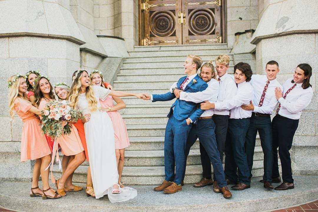Bride and bridesmaids pulling a groom who is held back by groomsmen.