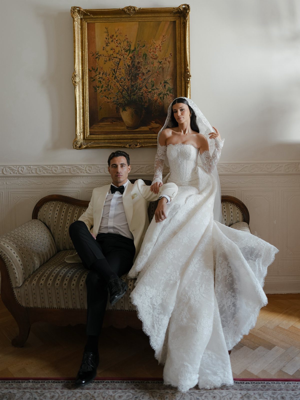 Bride and groom posing in a classic room with the dress train spread out.