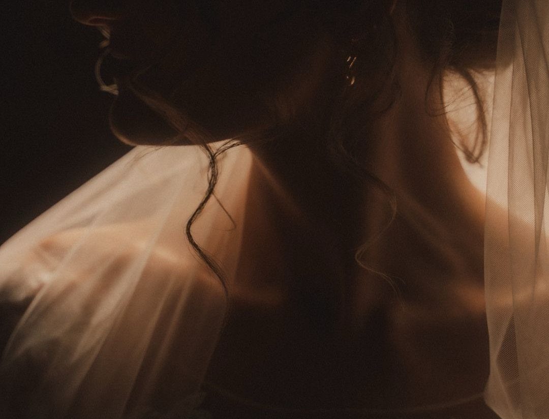 Bride in profile with dramatic shadows and warm light highlighting her veil.