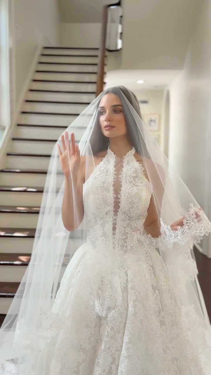 Bride in a white lace gown with a sheer veil draped over her head.