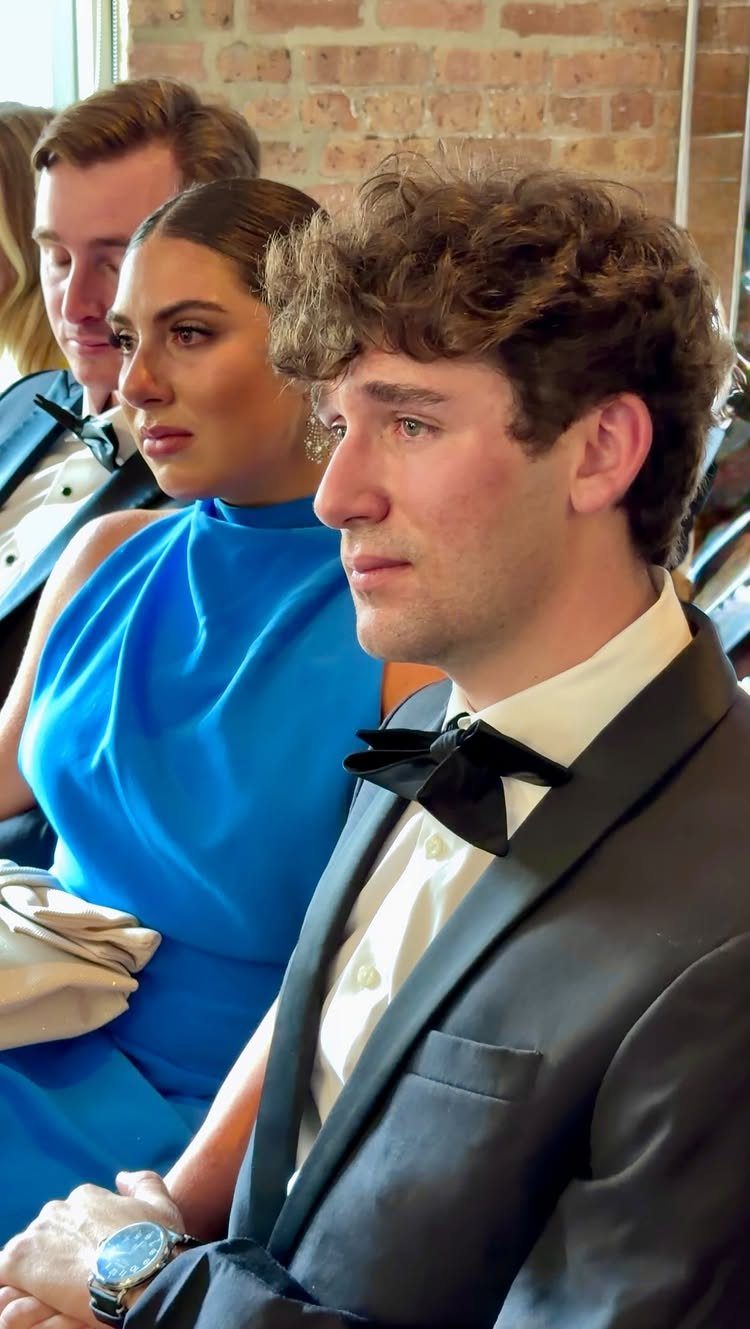 Tearful man in a tuxedo sitting next to a woman in blue dress.