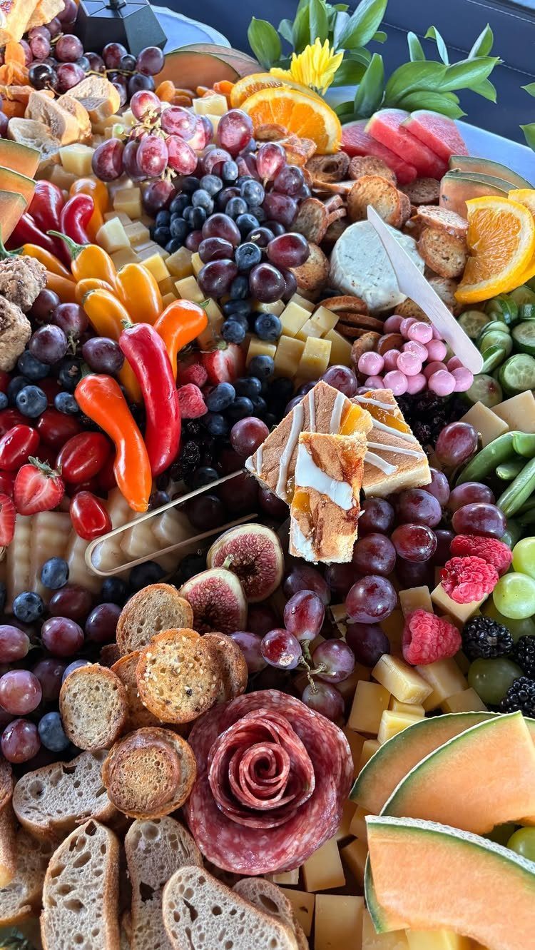 Charcuterie board with assorted fruits, cheeses, meats, and crackers arranged artistically.