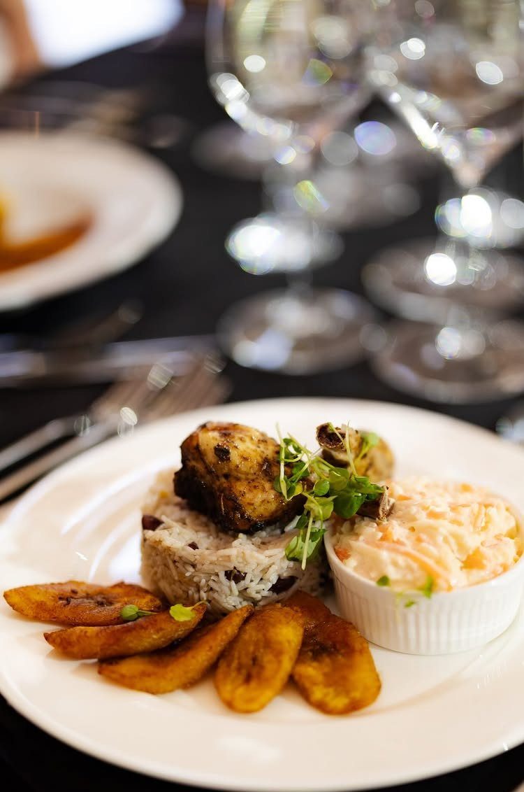 Grilled fish with rice, beans, plantains, and coleslaw on a white dinner plate.
