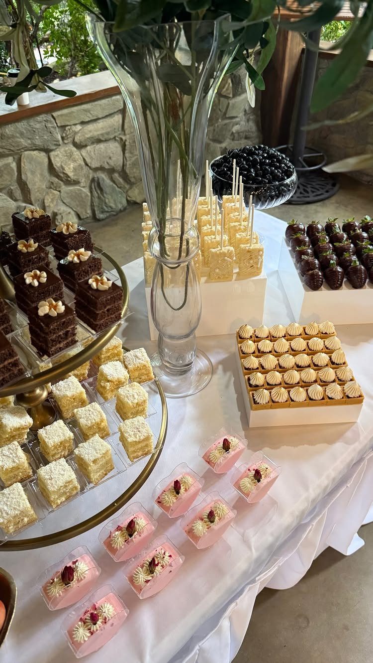 Assorted dessert platters with cakes and mousse on a white catered table.