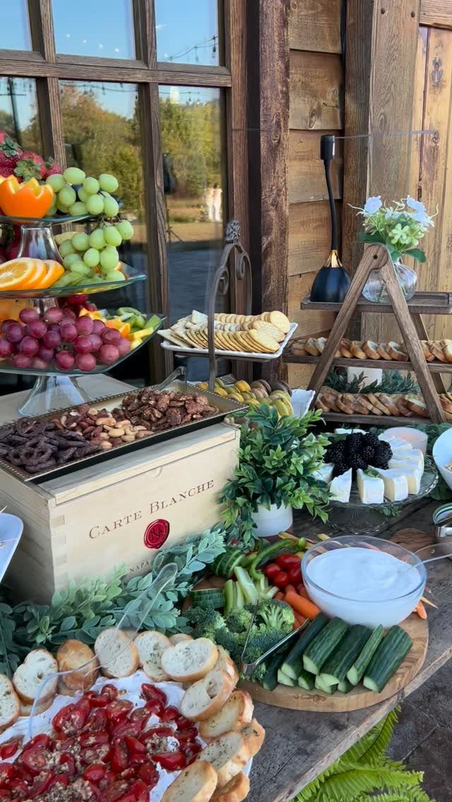 Charcuterie grazing table with fresh fruits, vegetables, cheeses, nuts, and crostini outdoors.