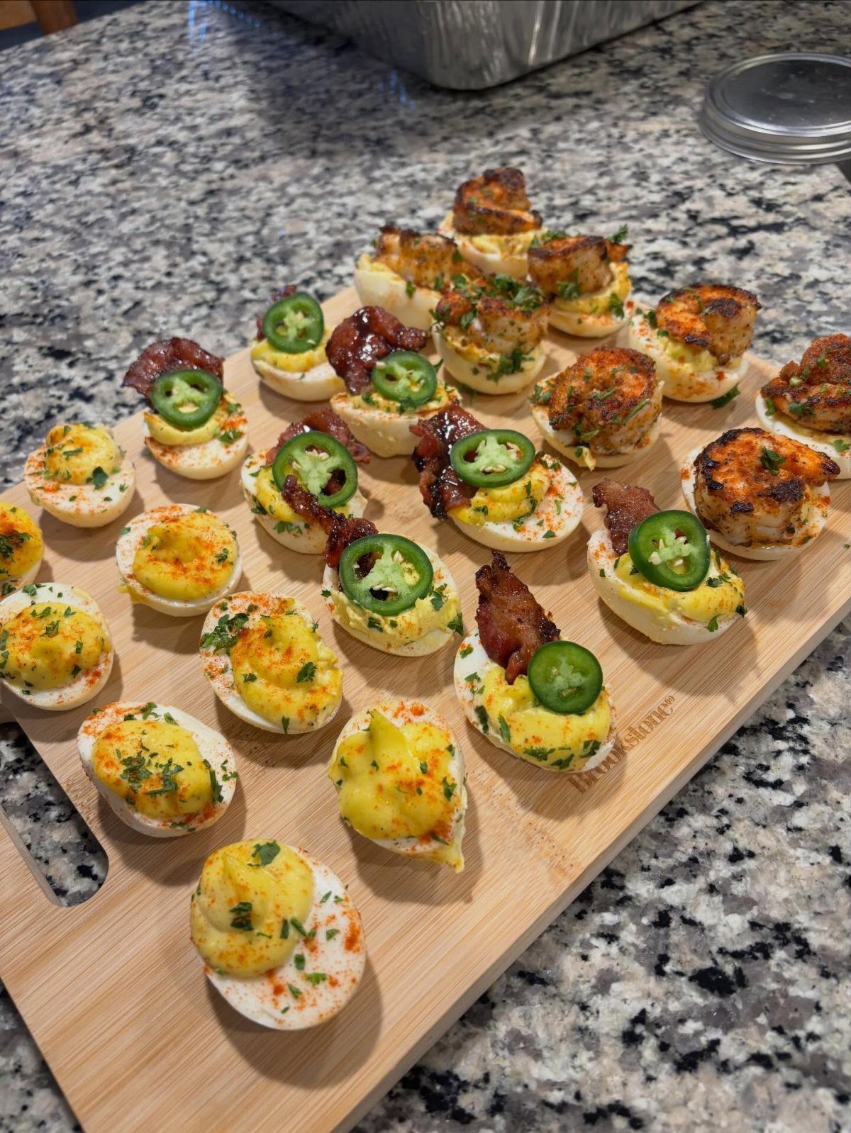Deviled eggs with bacon and jalapeño toppings arranged on a wooden serving board.