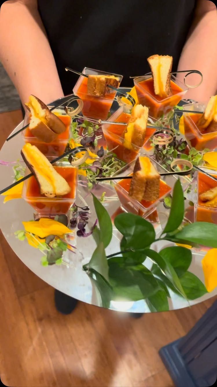 Tomato soup shooters with grilled cheese toast on a silver garnished platter