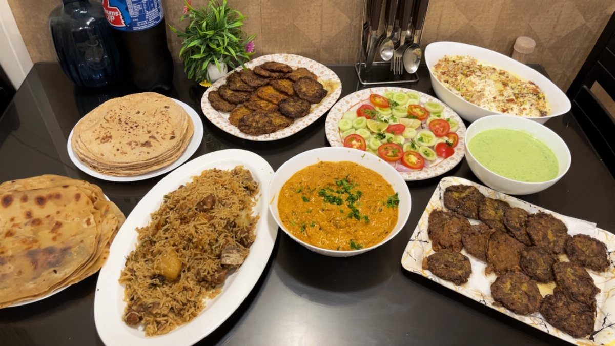 Assorted Indian dishes including biryani, curry, and flatbreads arranged on a black table.