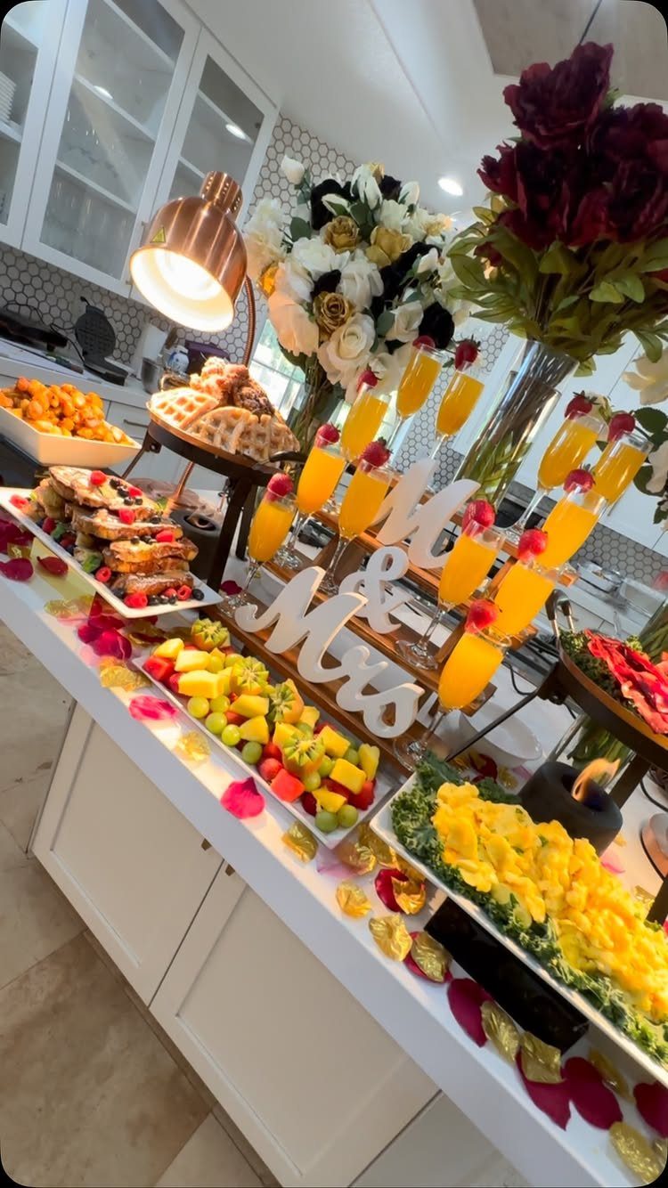 Wedding food spread with fruit, pastries, and orange juice on a white counter.