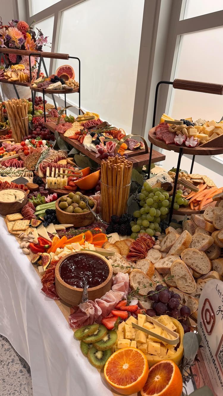 Charcuterie spread with meats, cheeses, and fruits on a white wedding table