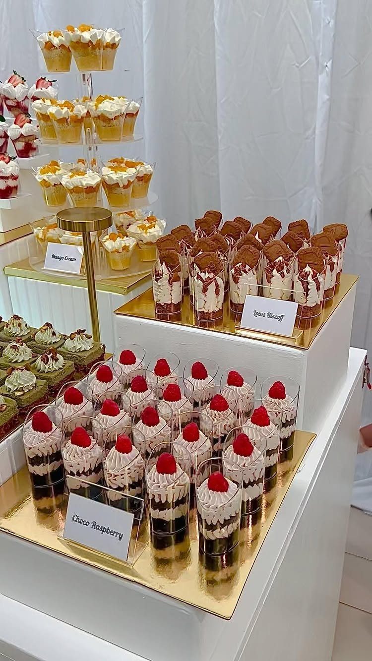 Dessert buffet with raspberry cream cups, chocolate mousse, and cake parfaits on trays.