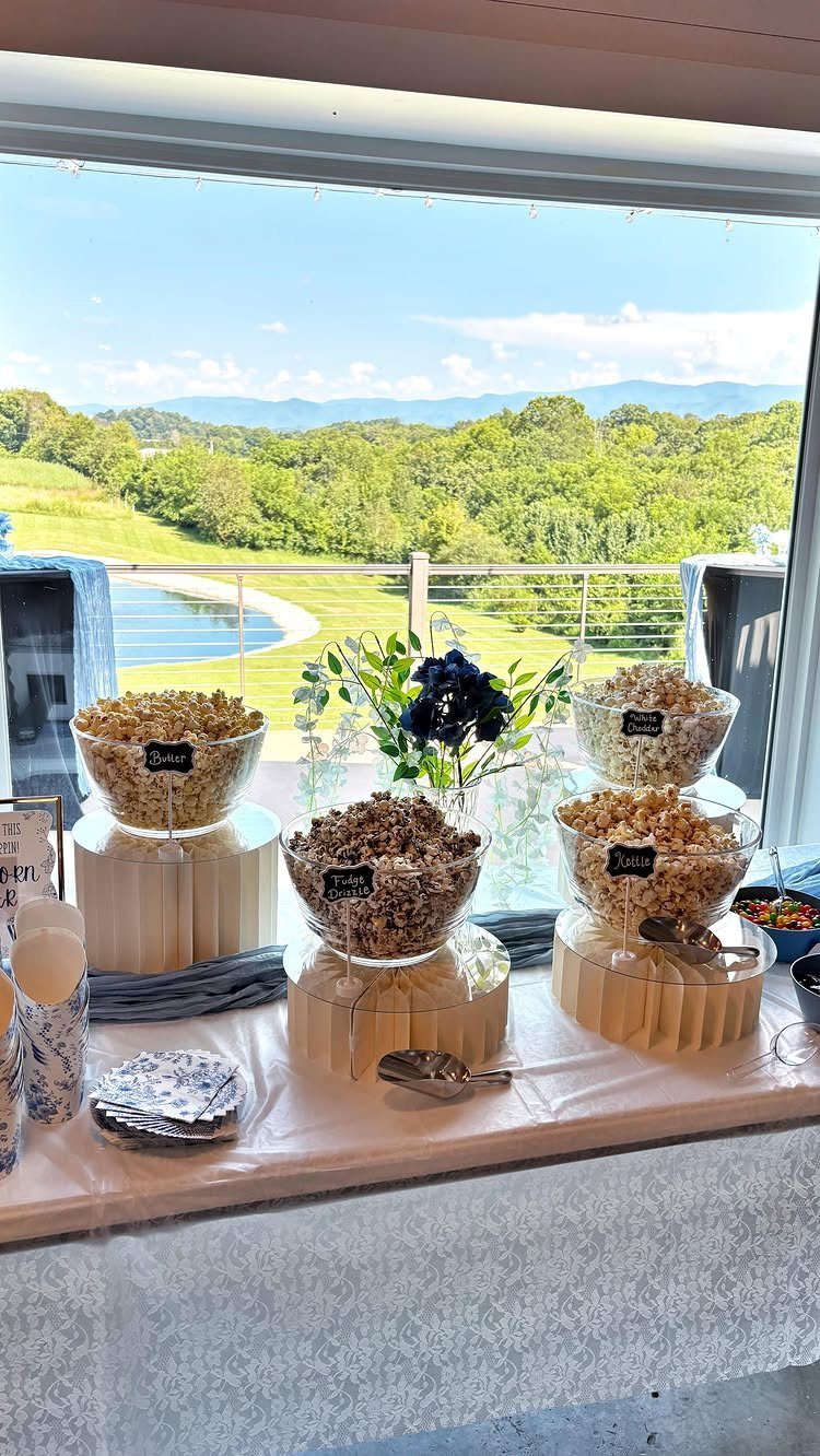 Popcorn station with four bowls of seasoned popcorn on a white table.