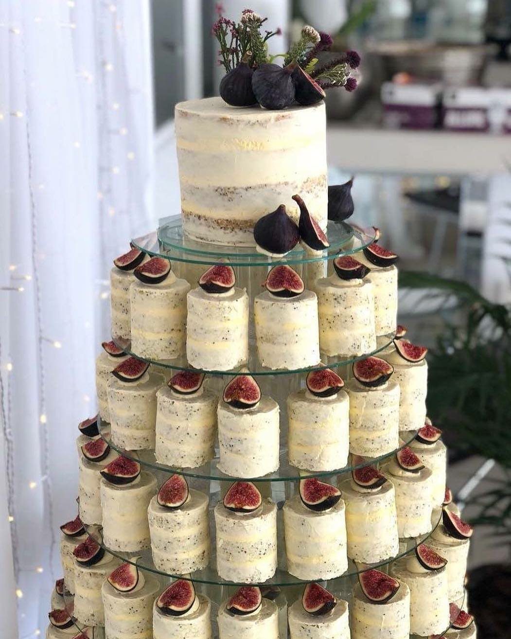 Stacked mini cheesecakes topped with fig slices forming a tiered wedding cake display.