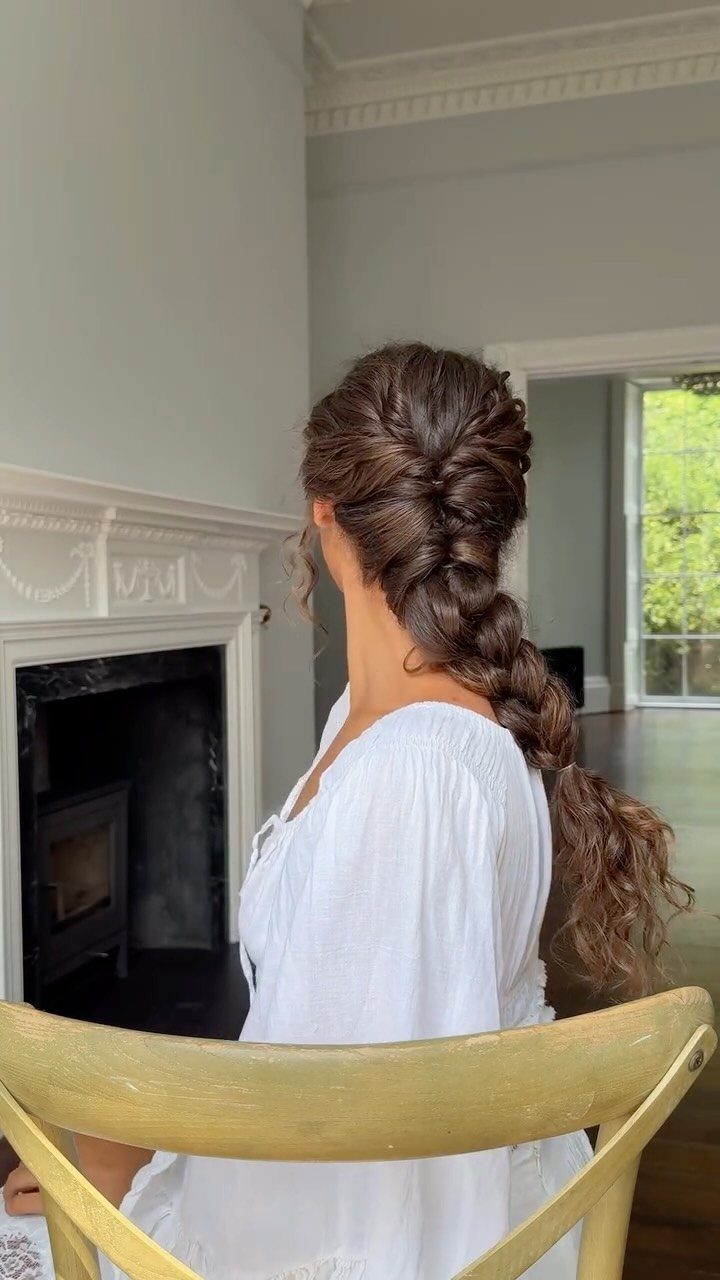 Woman with brown hair styled in a curly fishtail braid wearing white dress