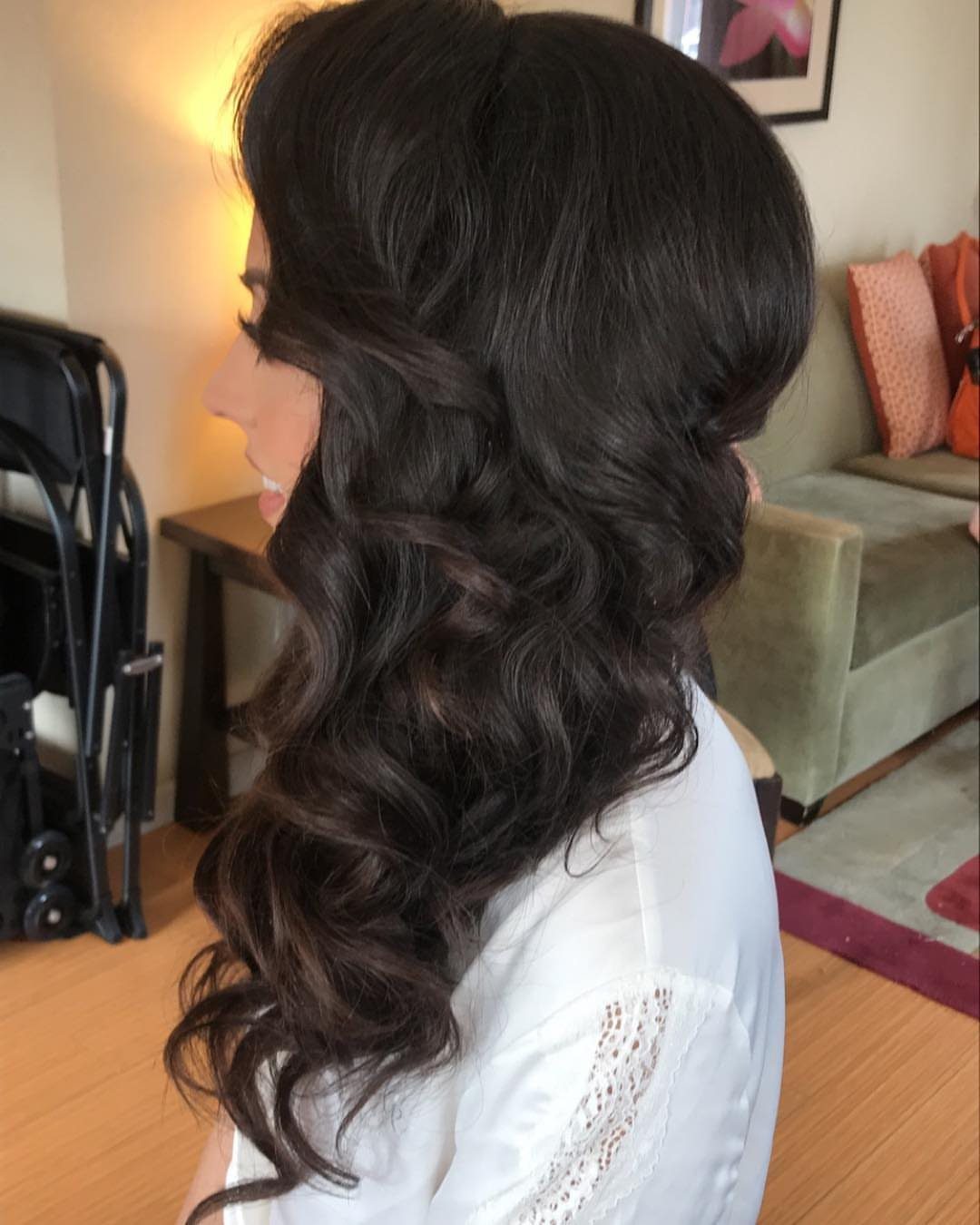 Woman with long dark brown curly hair swept to one side over her shoulder