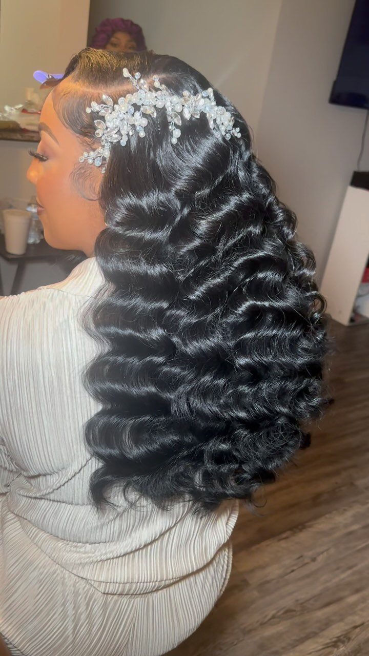 Woman with long black vintage glamour waves and a silver floral hair accessory.