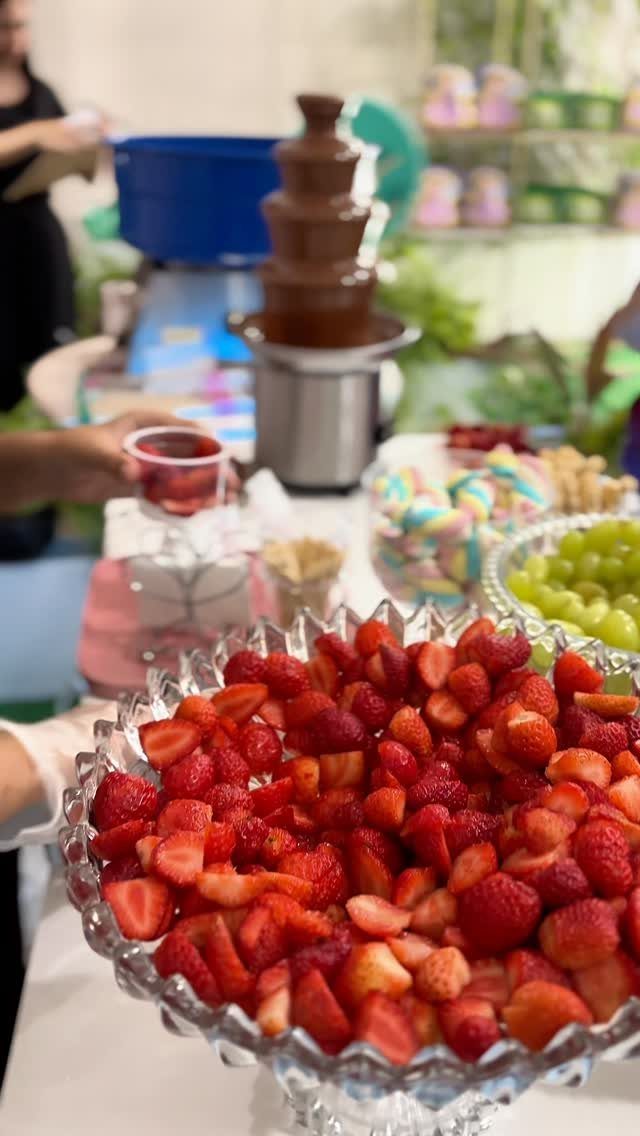 Chocolate fountain with bowls of fresh strawberries, grapes, and marshmallows on a table