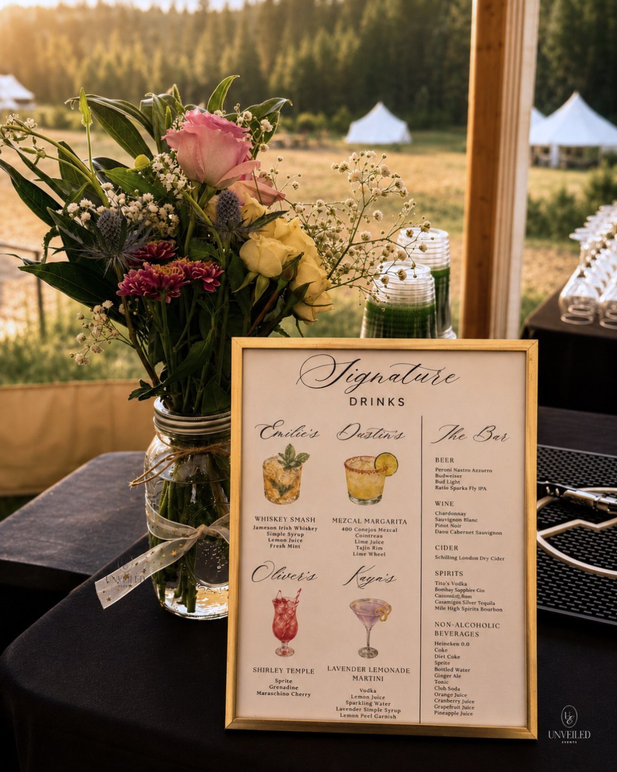 Signature drinks menu in gold frame next to floral bouquet on black table
