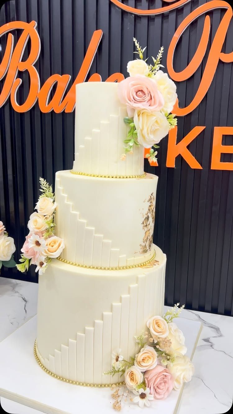 Three-tier white fondant wedding cake with sculpted stairs and pale pink roses.